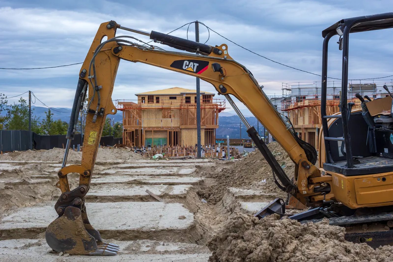 An excavator working beside a building under construction